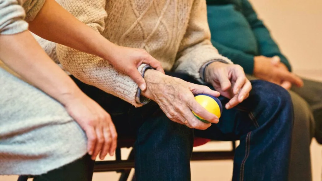 Krankenschwester hält die Hand eines Rentners in einem Pflegeheim in Tunesien